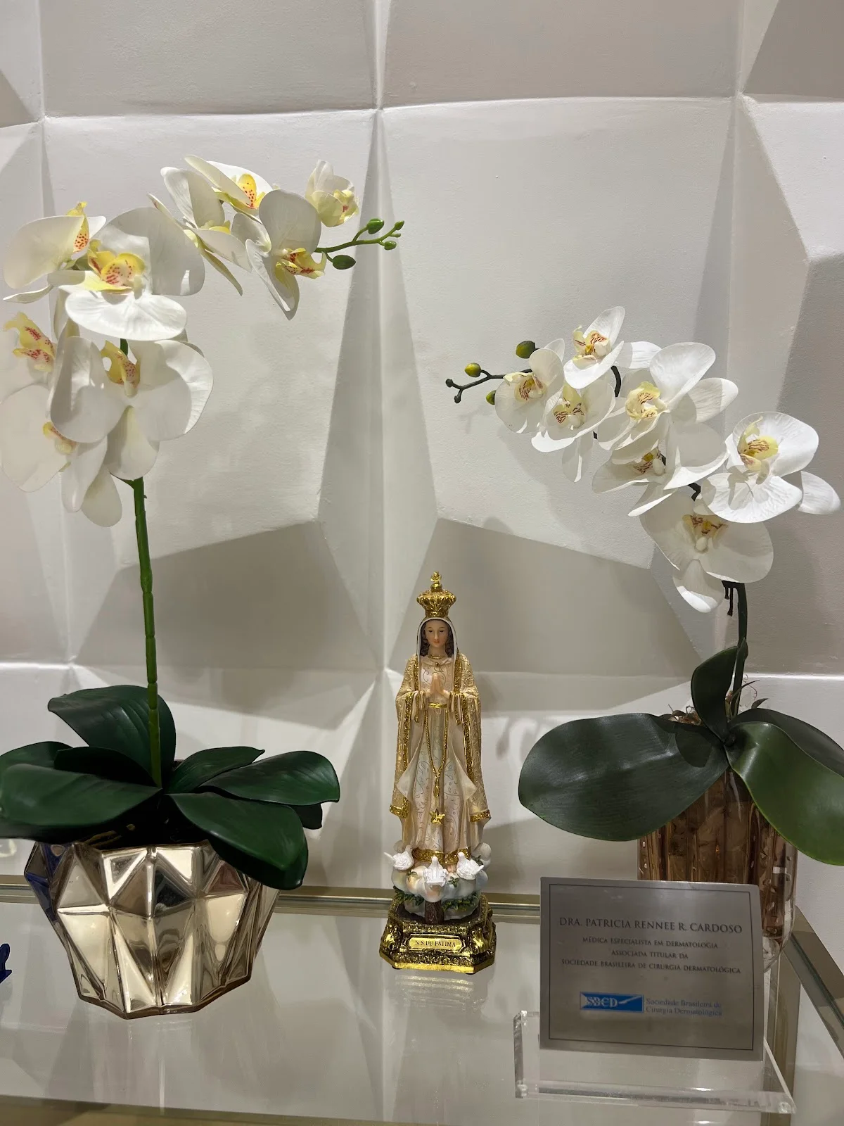 Orquídeas brancas em vasos dourados diante da parede em facetas.